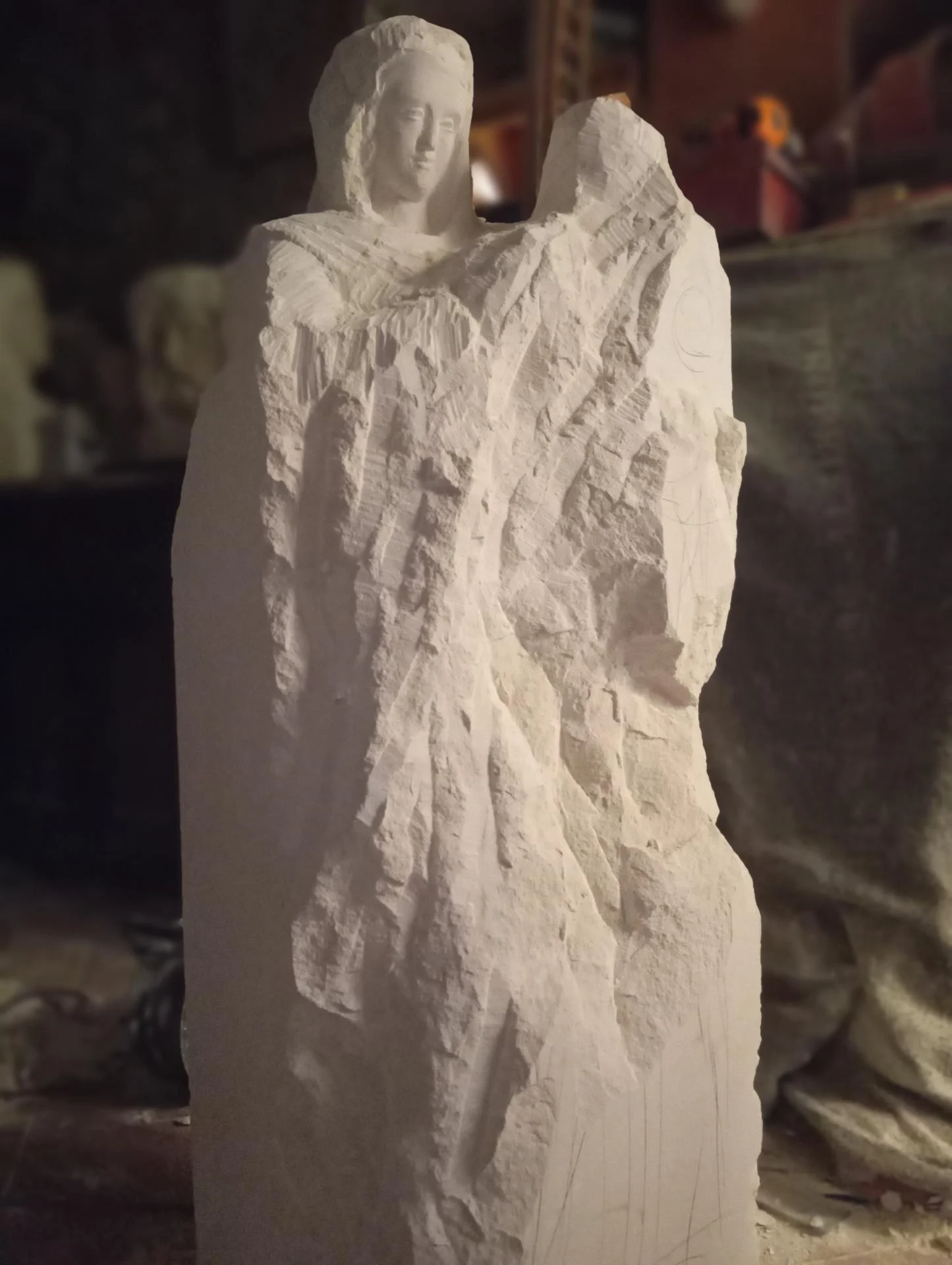 Dégrossissage du bloc — émergence du visage de la Vierge dans la pierre naturelle calcaire, sculpture en taille directe 120 cm, atelier Jean-Joseph Chevalier