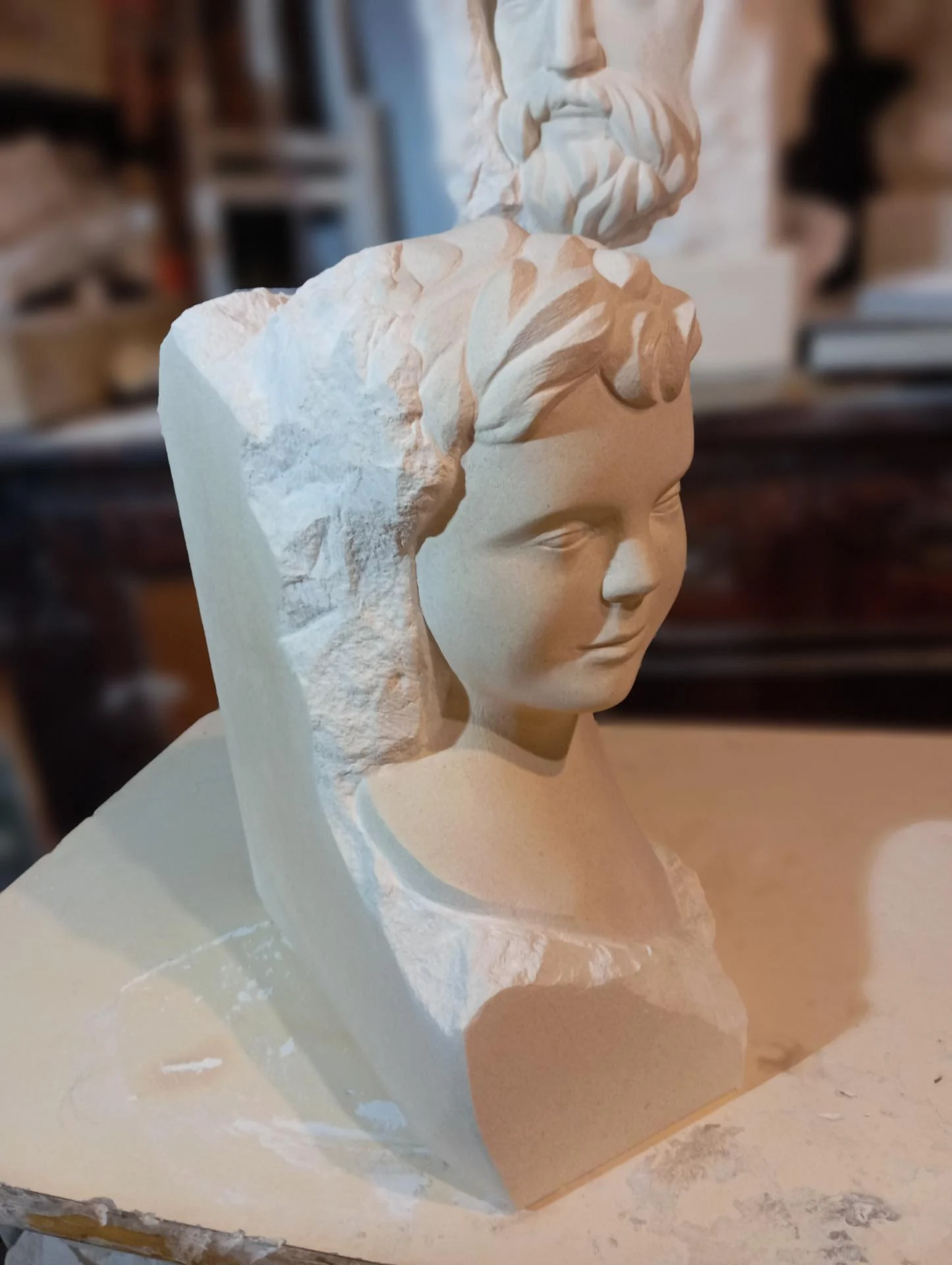 Buste d'enfant sortant de la pierre — le profil contre la masse brute du bloc : le non finito, la vie qui sort de la pierre. Taille directe, 50 cm, 2025, photographié à l'atelier. Sculpteur sur pierre Jean-Joseph Chevalier (Brignoles, Var, Provence).