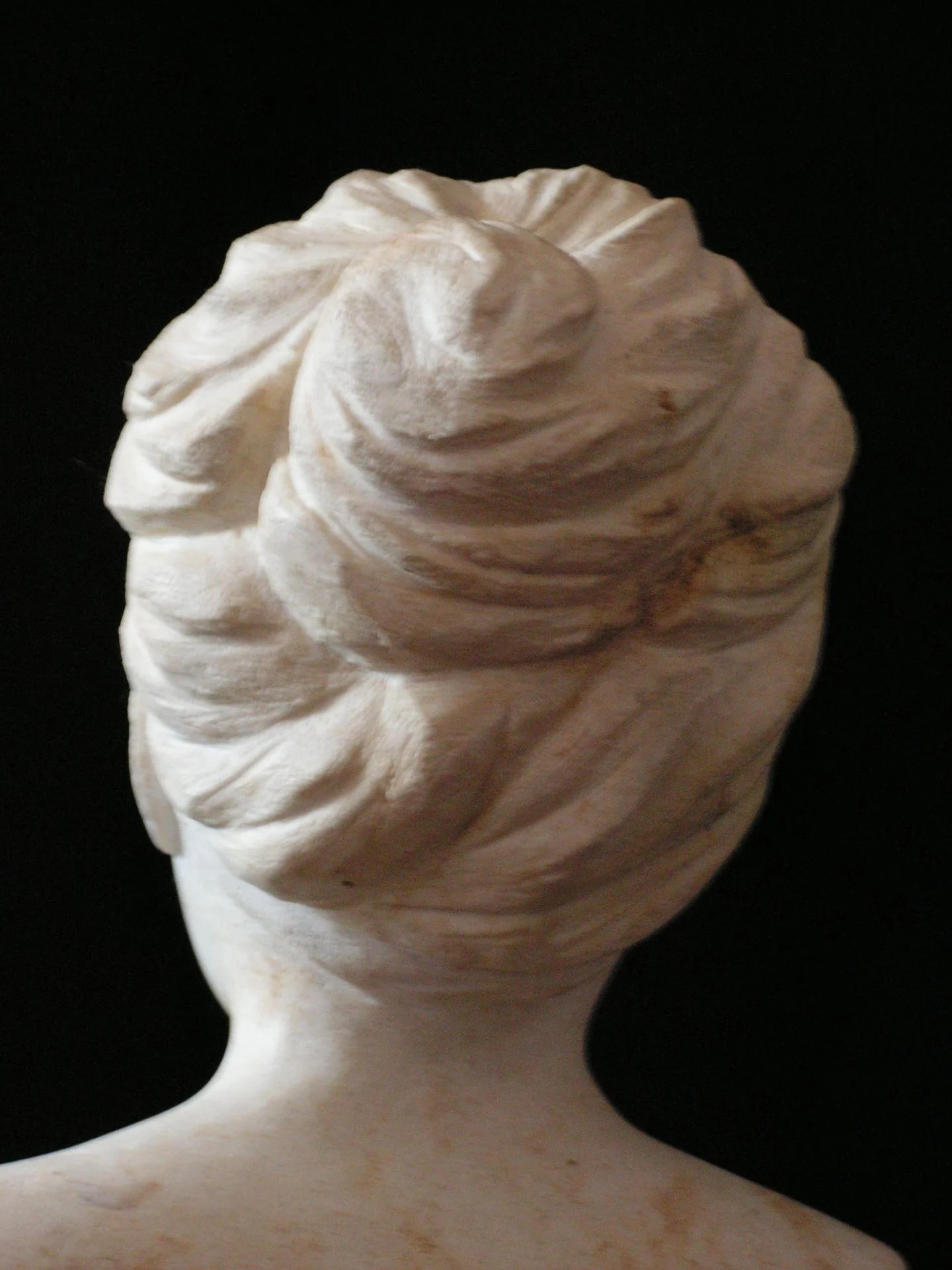 Buste de jeune fille, vue de l'arrière — le chignon plein cadre : les mèches torsadées et relevées, chacune travaillée au millimètre dans la pierre calcaire véritable. Le morceau de bravoure de la miniature, ronde-bosse complète. Taille directe, 15 cm, 2005. Sculpteur sur pierre Jean-Joseph Chevalier (Brignoles, Var, Provence).