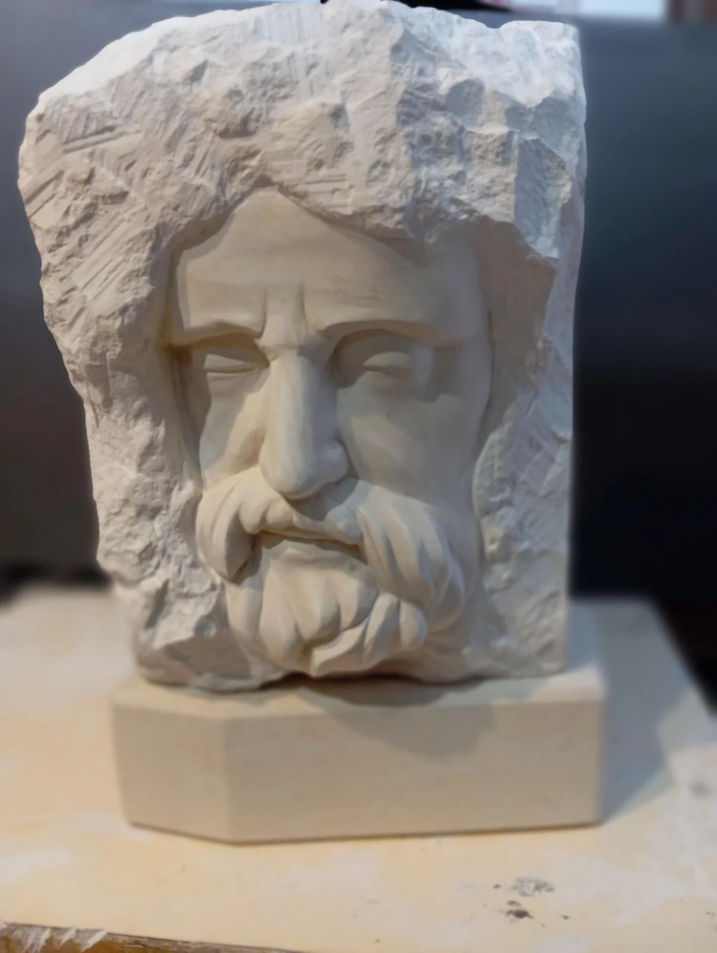 Le Repentir de saint Pierre, vue de face — les sourcils noués par la douleur, le regard chargé, la barbe et la moustache tombantes : le visage d'un homme brisé et déjà relevé, émergeant du bloc de pierre naturelle laissé brut. Non finito, taille directe, 50 cm, 2024. Sculpteur d'art sacré Jean-Joseph Chevalier (Brignoles, Var, Provence).