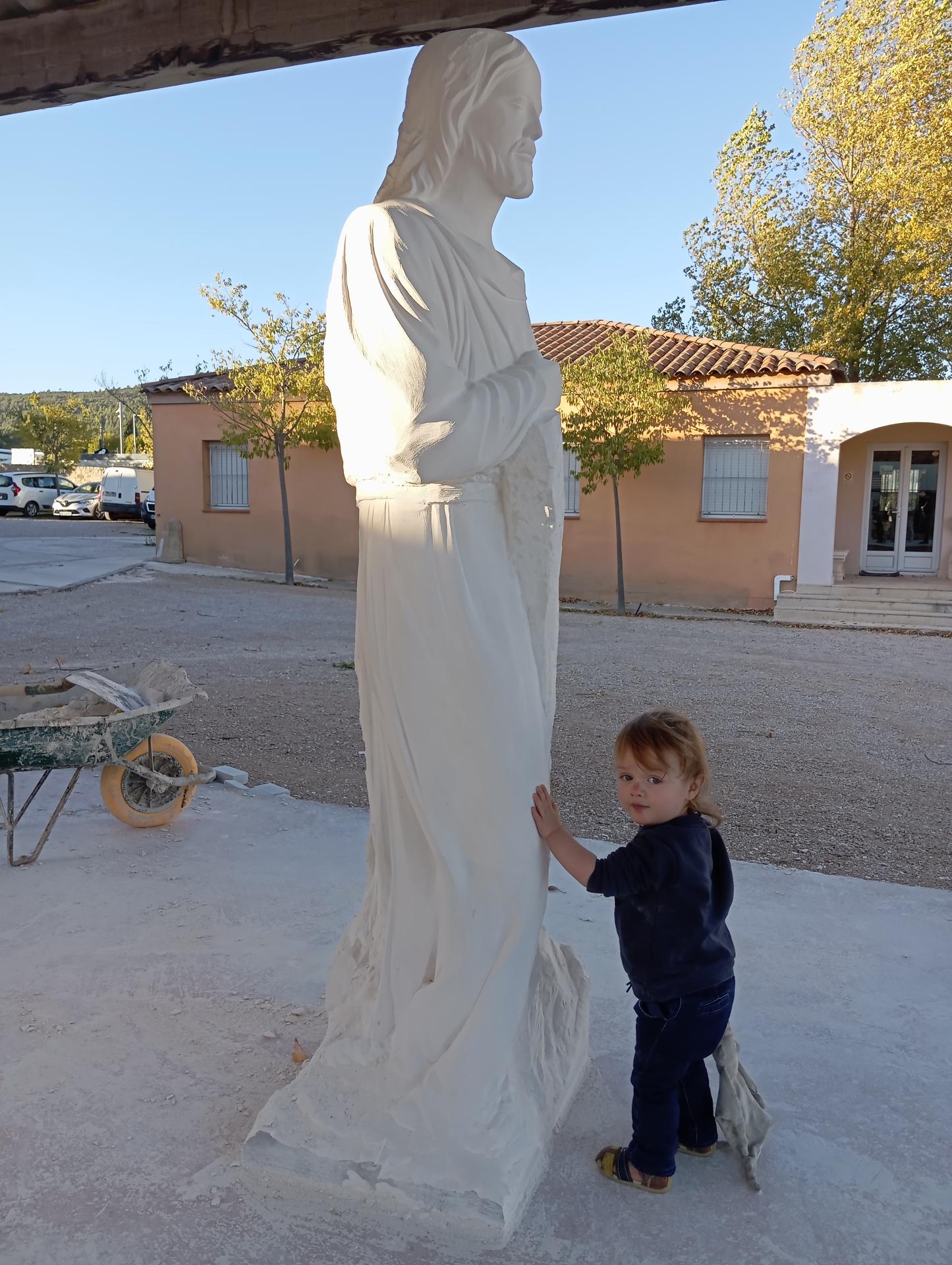 Le fils du sculpteur à côté du Christ charpentier en pierre calcaire 200 cm — échelle de la statue à l'atelier — Jean-Joseph Chevalier sculpteur