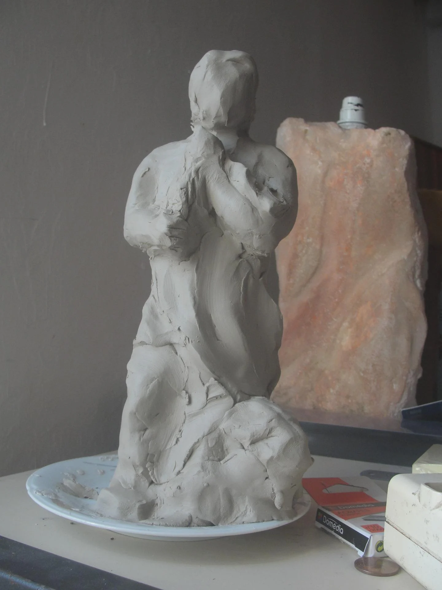 L'étude en argile de la statue Saint Jean — la maquette préparatoire modelée en terre dans l'atelier, figure tenant la coupe contre elle, avant le passage à la pierre. La pensée du sculpteur modelée du bout des doigts. Étape préparatoire de l'art sacré — abbaye de Lagrasse 2016 — Jean-Joseph Chevalier.