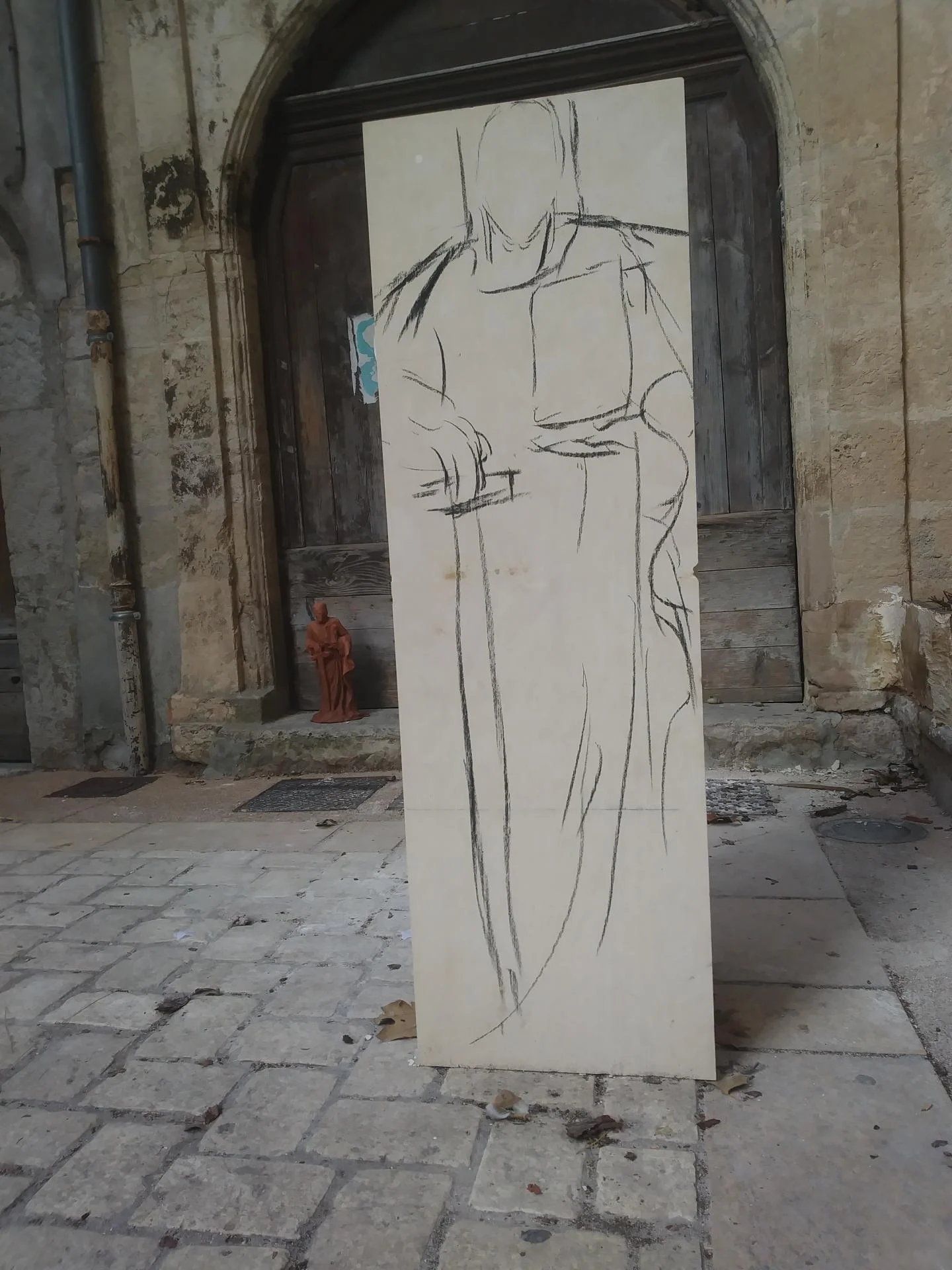 Bloc capable de pierre calcaire naturelle avec dessin grandeur nature de saint Paul tracé sur la face — mise au gabarit avant taille directe par un sculpteur sur pierre, devant l'atelier. Statue religieuse 140 cm pour l'abbaye Saint-Paul de Wisques. Sculpteur d'art sacré Jean-Joseph Chevalier.